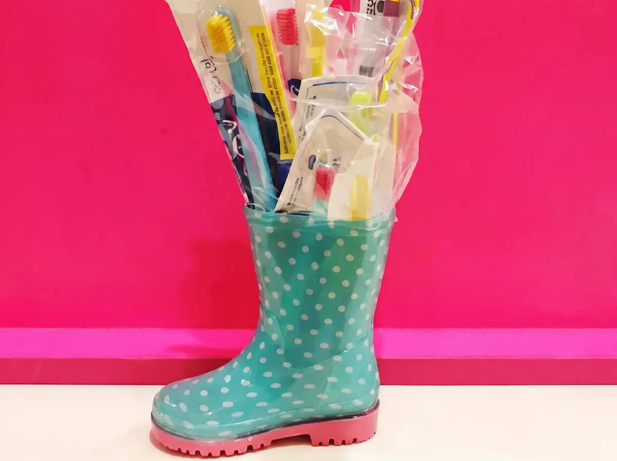 Türkiser Gummistiefel gefüllt mit verpackten Zahnbürsten